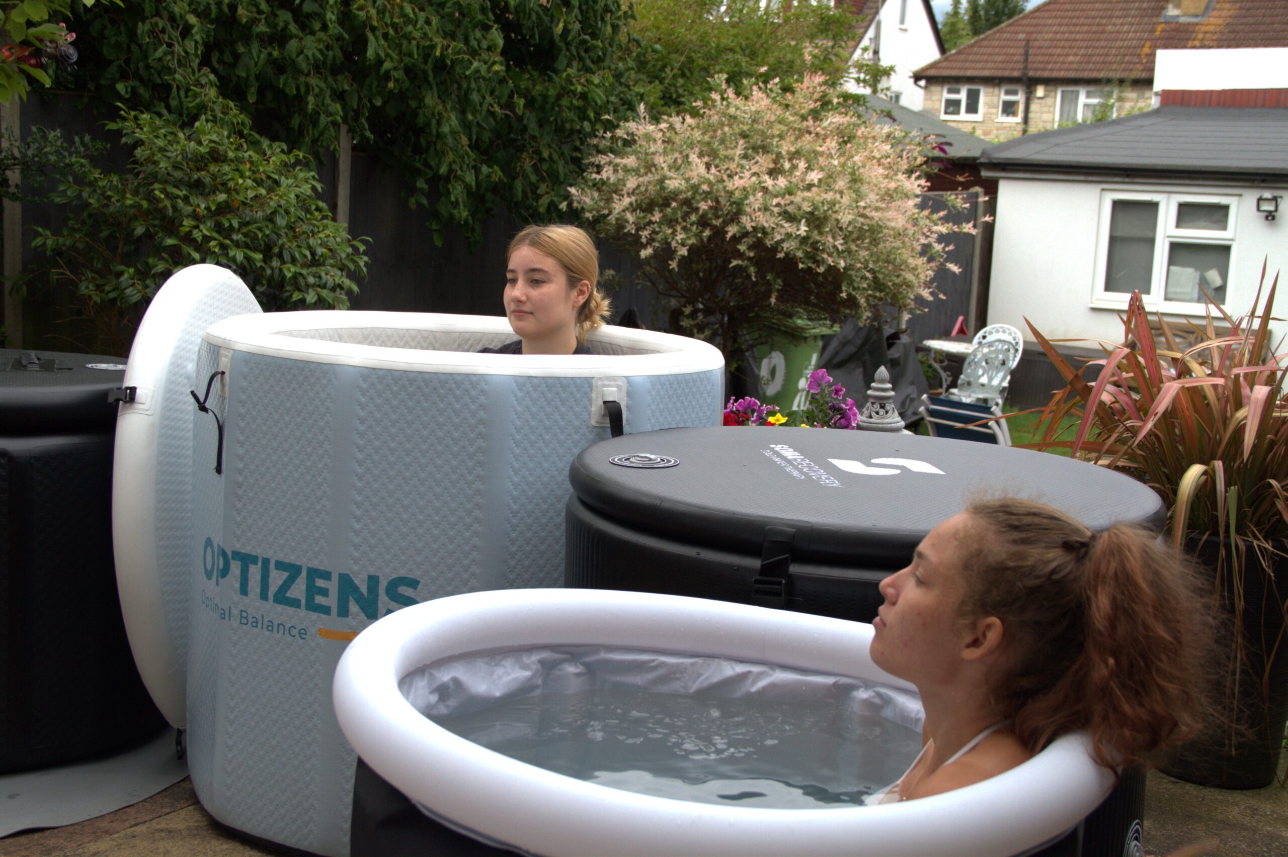 four ice baths in a semi circle with two young women in the tubs, relaxed and enjoying the ice baths.